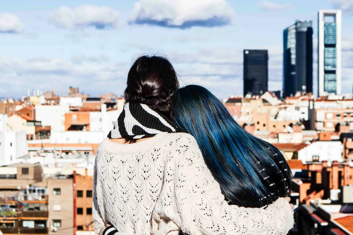 Dos mujeres abrazadas de espaldas contemplando los tejados de Madrid